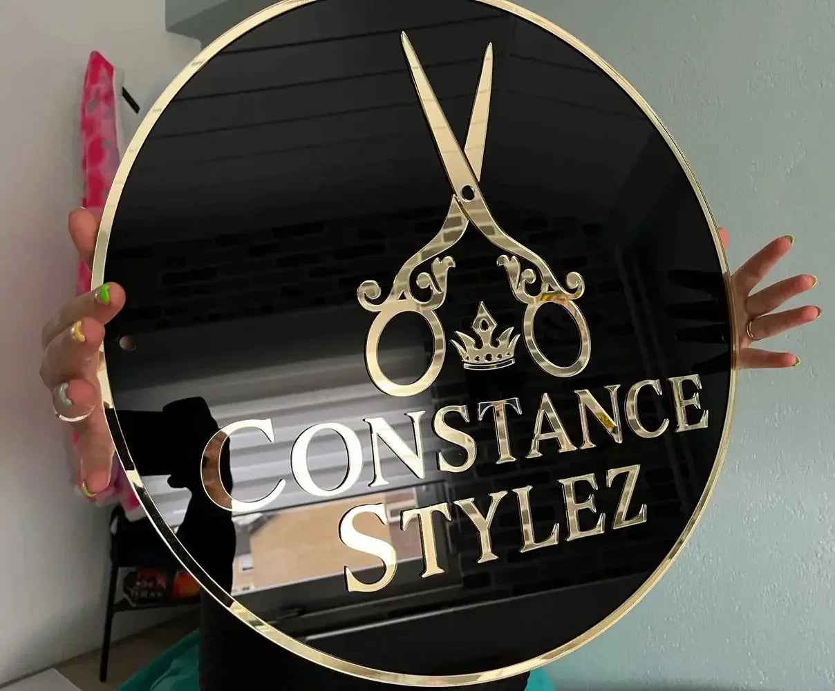 Custom round black sign with gold scissors, crown, and 'Constance Stylez' text for salon branding