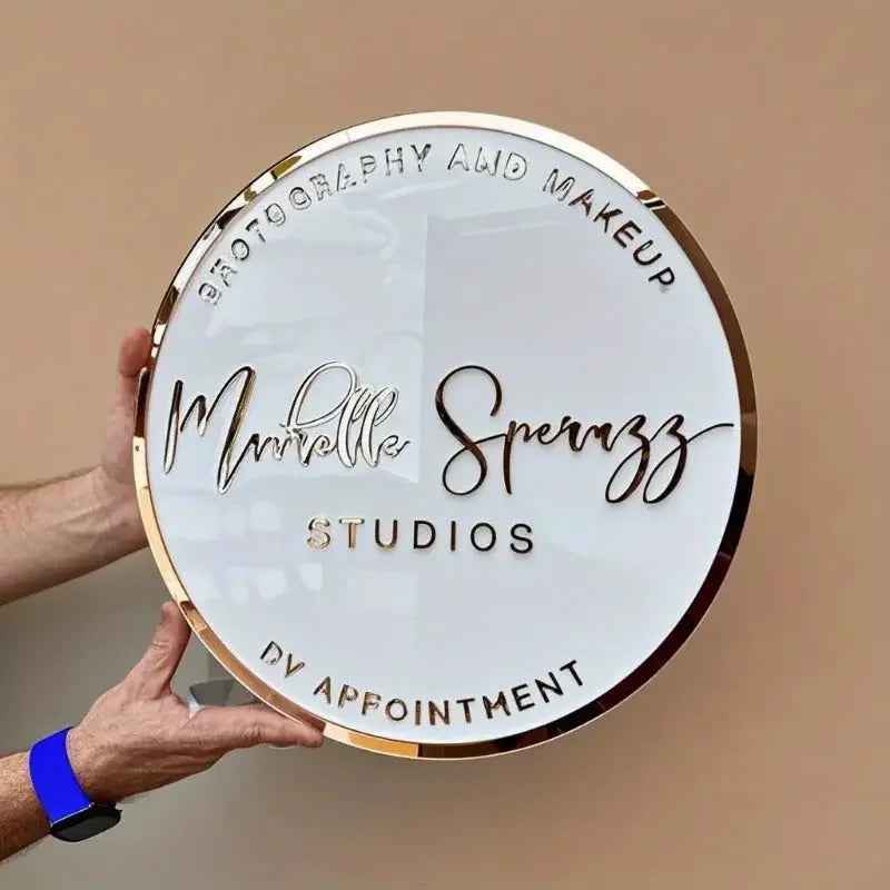 Custom round acrylic sign with gold trim for photography and makeup studio, held by hands