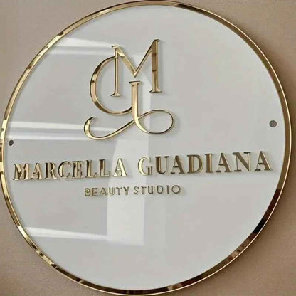 Elegant gold monogram sign for Marcella Guadiana Beauty Studio, round white plaque with metallic lettering