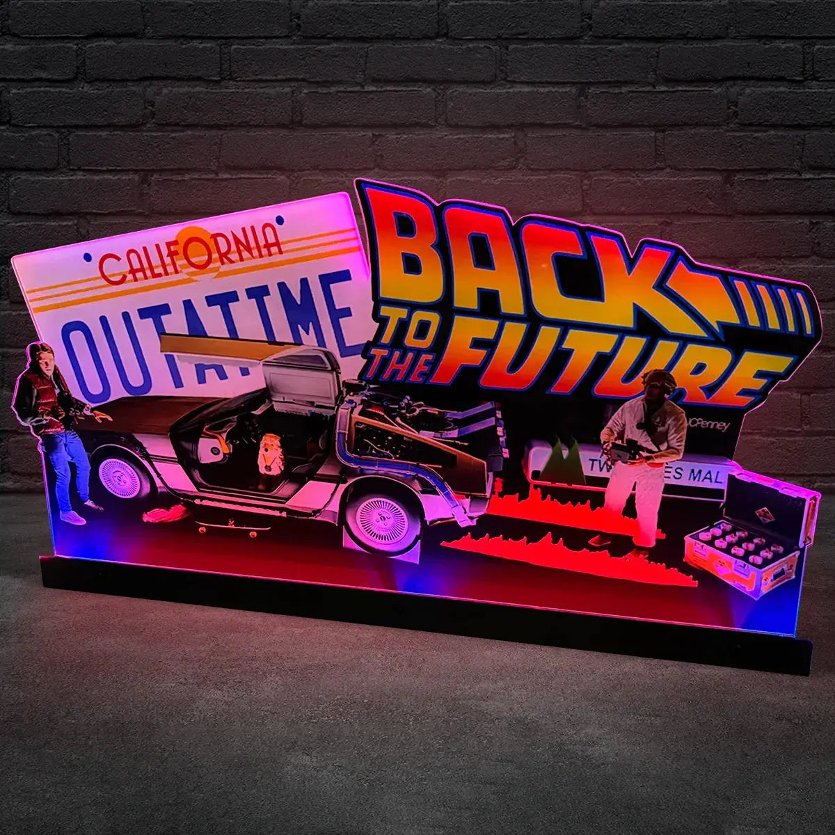 Light-up display of a car from 'Back to the Future' with 'Outta Time' sign and characters against a brick wall.
