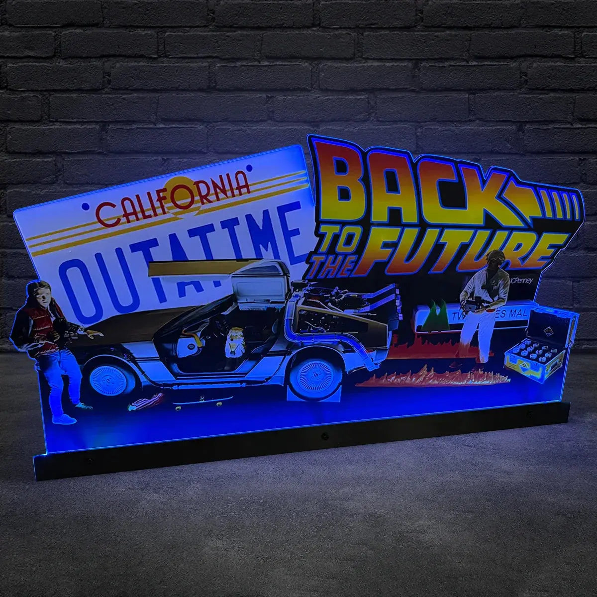 Back to the Future-themed display with DeLorean car, characters, and license plate against a brick wall.