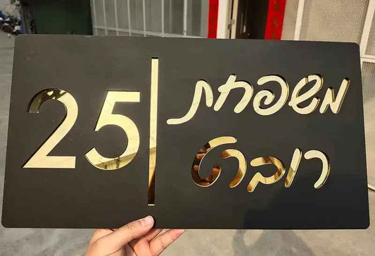 Custom black and gold metal sign with cutout numbers and script text, held in hand