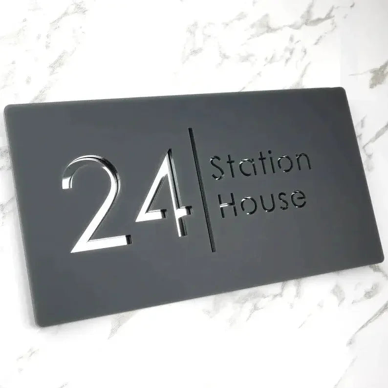 Modern black house number plaque with '24 Station House' in sleek silver lettering on marble