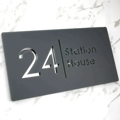 Modern black house number plaque with '24 Station House' in sleek silver lettering on marble