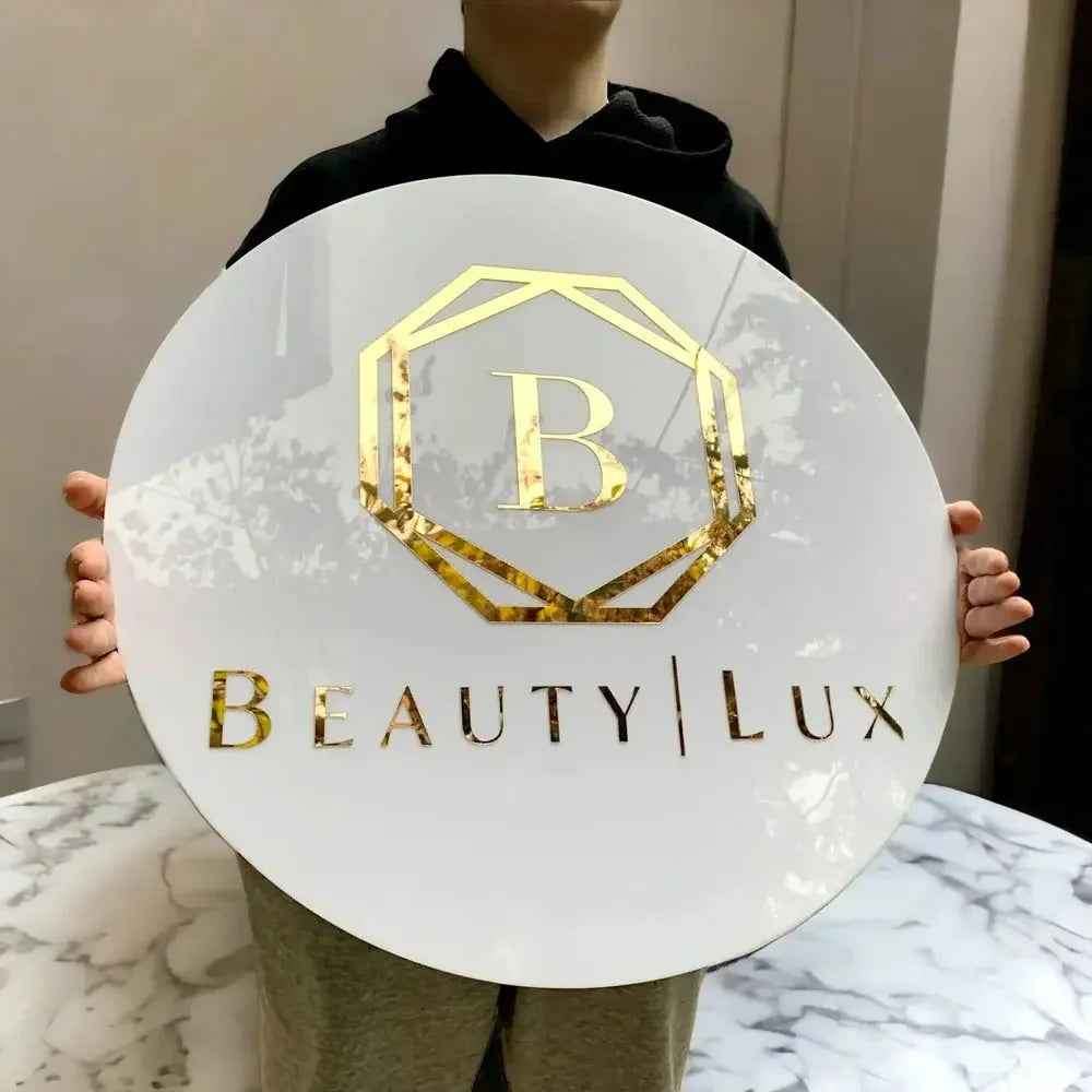 Custom round white sign with gold 'B' logo and 'BEAUTY | LUX' text, held by person near marble table