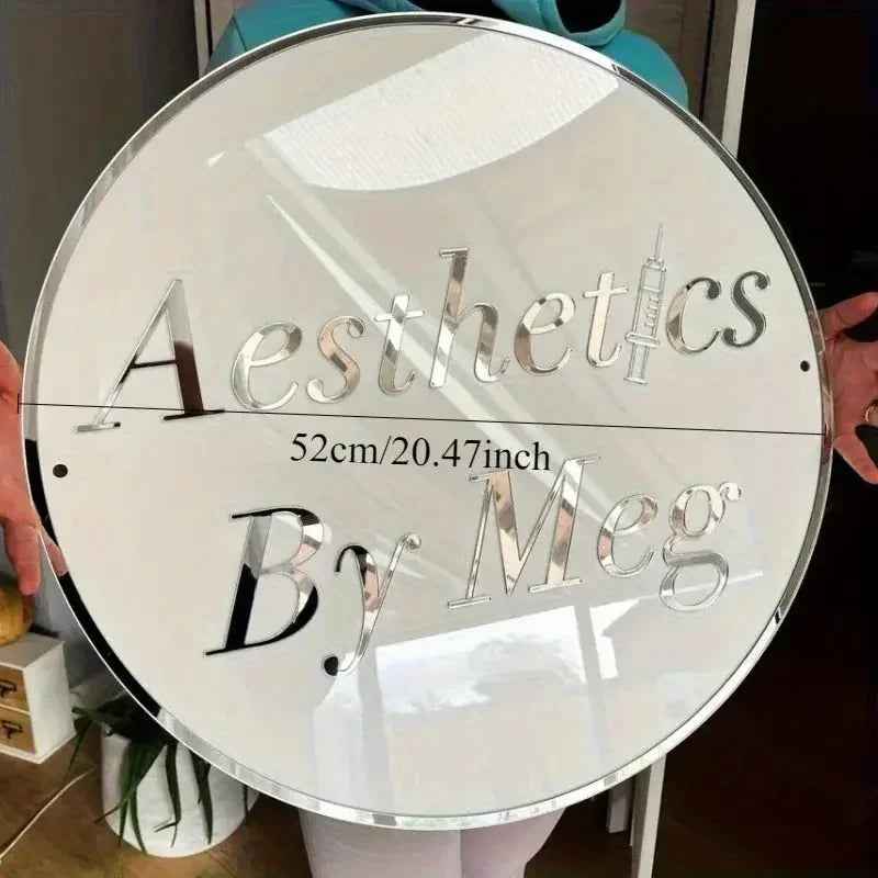 Round mirrored sign with 'Aesthetics By Meg' text, 52cm diameter, held by person