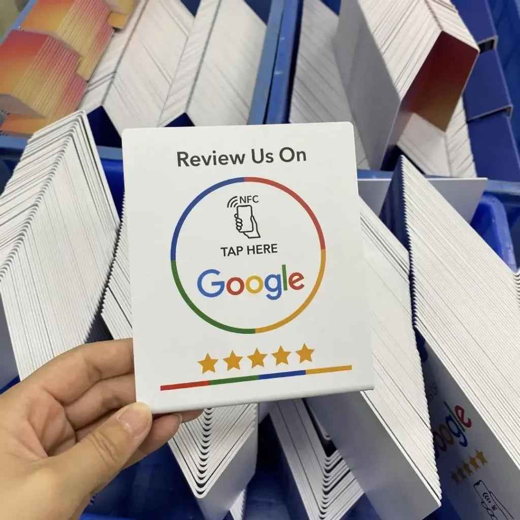 NFC Google review card with tap-to-rate feature, held over stacks of printed cards